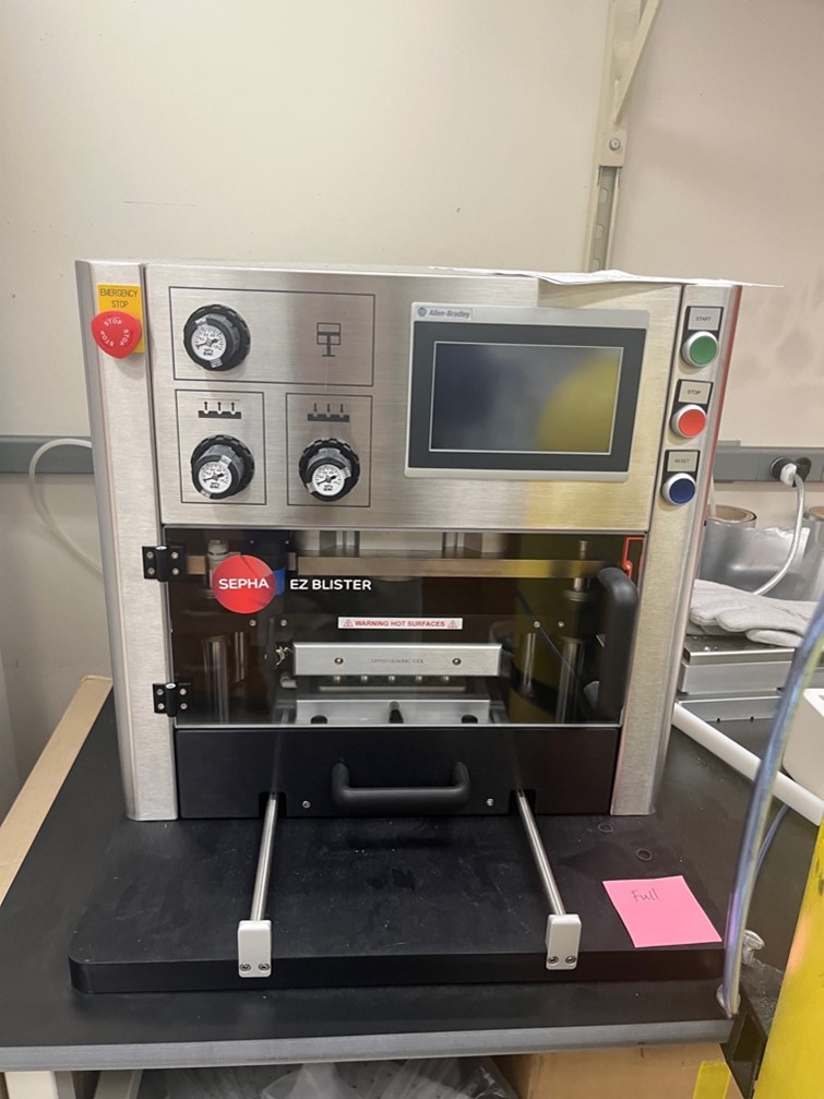 Sepha EZ Blister machine on a laboratory bench, featuring pressure gauges, a touchscreen control panel, and an emergency stop button