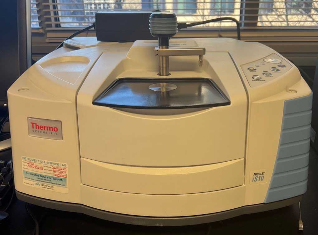 Thermo Scientific Nicolet i.S.10 Fourier-transform infrared spectrometer on a lab bench near a window, with a sample plate under the arm