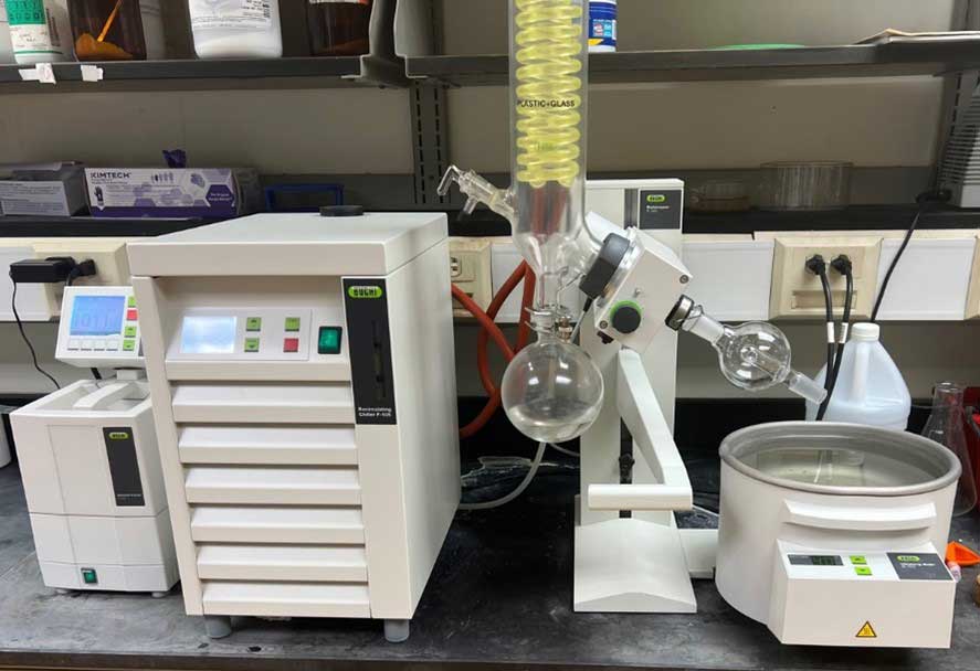 Büchi rotary evaporator setup with condenser coil, round-bottom flasks, and temperature control unit on a lab bench