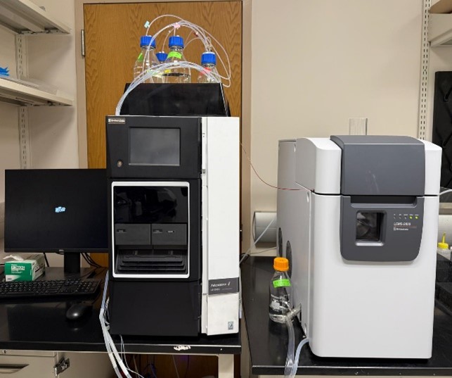 Shimadzu Prominence H.P.L.C. system with connected computer and solvent bottles on top, used for liquid chromatography analysis in a lab