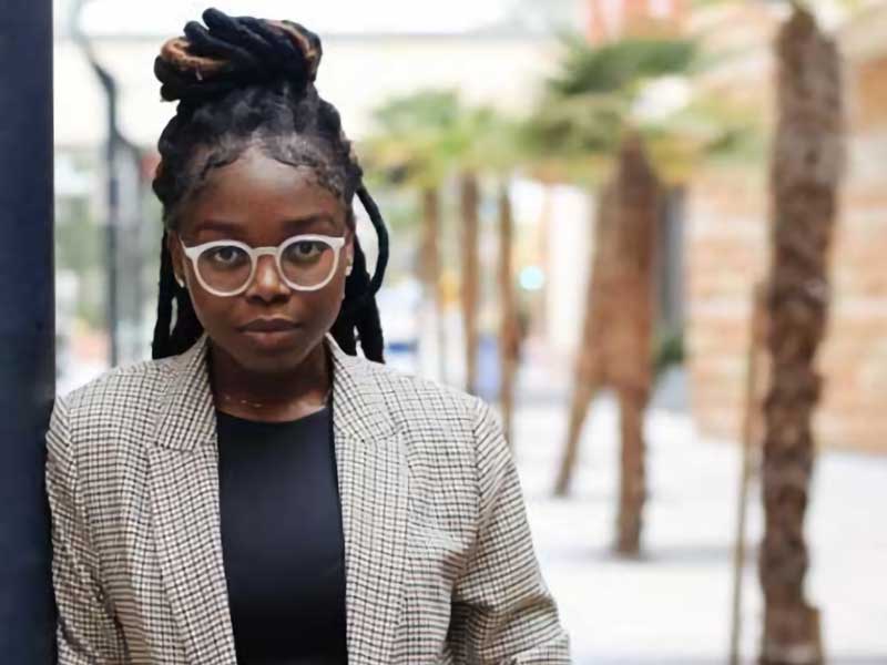 akua donkor standing outdoors on a palm tree–lined walkway