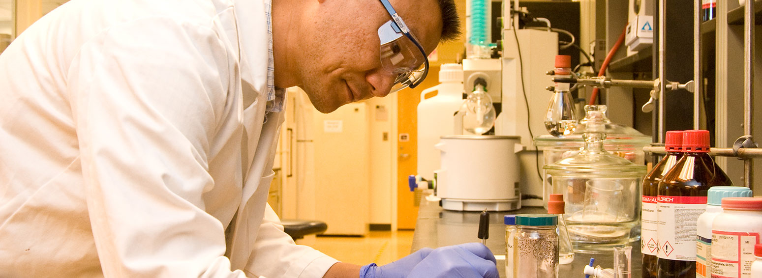 a lab worker wearing protective eyewear works on a lab task using his hands